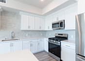 Thumbnail 34 of 88 - A modern kitchen with white cabinets and a stainless steel refrigerator.