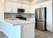 Thumbnail 2 of 88 - A modern kitchen with a white island and stainless steel appliances.