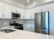 Thumbnail 19 of 88 - A modern kitchen with a stainless steel refrigerator, microwave, and oven.