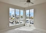 Thumbnail 17 of 88 - A room with a ceiling fan and large windows overlooking a cityscape.
