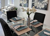 Thumbnail 8 of 35 - a dining room with a glass table and chairs and paintings on the wall