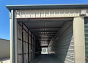 Thumbnail 10 of 11 - The inside of a storage unit with clean concrete floor and metal walls. Doors at both ends of the unit are open.