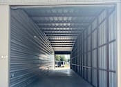 Thumbnail 9 of 11 - The inside of a storage unit with clean concrete floor and metal walls. This unit has doors at both ends open.