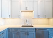 Thumbnail 2 of 8 - a white and blue kitchen with blue cabinets and a sink