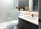 Thumbnail 10 of 22 - A modern bathroom with a white sink and a walk-in shower.