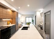 Thumbnail 18 of 22 - A modern kitchen with a black oven and a long white countertop.