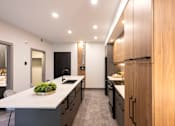 Thumbnail 20 of 22 - A modern kitchen with a large island and wooden cabinets.