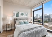 Thumbnail 1 of 35 - A bedroom with a large bed and a city view through the window.