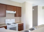 Thumbnail 4 of 20 - View of kitchen showing electric stove, double kitchen sink, wood cabinetry, and a portion of the breakfast bar