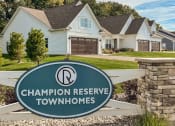 Thumbnail 2 of 22 - Exterior of Champion Reserve Townhomes near the Gillis Road entrance. White townhomes with attached 2-car garages.
