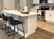 Thumbnail 3 of 22 - Interior of Champion Reserve Townhome  with view of well equipped kitchen with stainless steel appliances, quartz countertops, and breakfast bar/kitchen island.