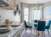 Thumbnail 11 of 31 - a kitchen and dining room with a stove and a table and chairs