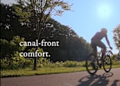 Thumbnail 26 of 29 - A person riding a bicycle on the Erie Canal path near Westport Crossing in Pittsford, NY