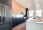 Thumbnail 6 of 29 - A modern kitchen with a black refrigerator and wooden cabinets.