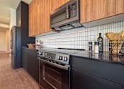 Thumbnail 7 of 29 - A modern kitchen with dark wood cabinets and black appliances.