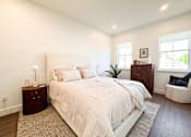 Thumbnail 10 of 29 - A bedroom with a large bed, a nightstand, and a chair.