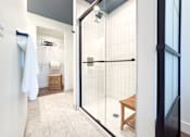 Thumbnail 11 of 29 - A bathroom with a walk in shower and a towel rack.