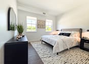 Thumbnail 15 of 29 - A bedroom with a large bed and a black and white patterned rug.