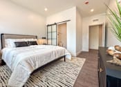 Thumbnail 16 of 29 - A bedroom with a large bed and a black and white striped rug.