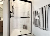 Thumbnail 18 of 29 - A white tiled bathroom with a walk in shower.