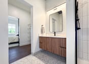Thumbnail 17 of 29 - A bathroom with a mirror, sink, and a bedroom in the background.