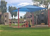 Thumbnail 2 of 8 - a playground with a blue canopy in a park