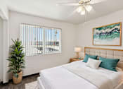 Thumbnail 33 of 42 - A bedroom with a large bed, a ceiling fan, and a plant.