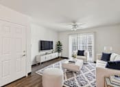 Thumbnail 32 of 42 - A living room with a white couch, a white chair, a white ottoman, a white rug, a white ceiling fan, a white door, a white cabinet, a white television, and a white wall.