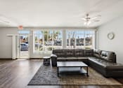 Thumbnail 36 of 42 - A black leather couch sits in a living room with a ceiling fan and a large window.