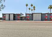 Thumbnail 16 of 42 - A building with a red and grey facade and palm trees in the background.