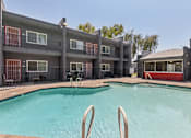 Thumbnail 12 of 42 - A swimming pool in front of a building with a red and black exterior.