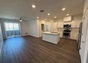 Thumbnail 13 of 16 - A spacious kitchen with white cabinets and a wooden floor.