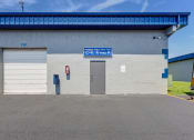 Thumbnail 11 of 29 - the front of a building with two garage doors and a blue sign on the side
