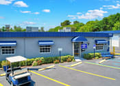 Thumbnail 16 of 29 - a blue building with a parking lot and a blue roof