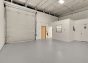 Thumbnail 19 of 29 - a large empty room with a garage door and a door to a hallway