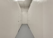 Thumbnail 20 of 29 - a long hallway with white walls and doors and a gray floor