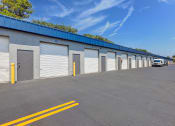 Thumbnail 26 of 29 - the side of a warehouse building with roller shutter doors and a truck parked outside