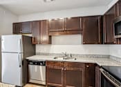 Thumbnail 10 of 60 - A kitchen with brown cabinets and a stainless steel refrigerator at Venue at 109 Apartments, Lebanon , TN