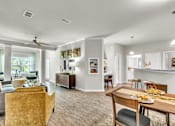 Thumbnail 5 of 39 - A well-lit living room with a dining area and kitchen in the background.