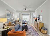 Thumbnail 2 of 48 - A living room with a grey couch, a brown chair, a white side table and a rug.
