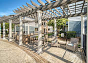 Thumbnail 38 of 41 - A patio with a white pergola and chairs.