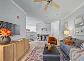 Thumbnail 1 of 48 - A living room with a grey couch and a wooden cabinet.