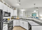 Thumbnail 14 of 39 - A kitchen with white cabinets and black appliances.