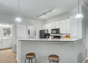 Thumbnail 14 of 48 - A kitchen with white cabinets and a granite countertop.