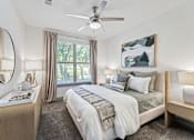 Thumbnail 8 of 48 - A bedroom with a large bed, a ceiling fan, and a painting on the wall.