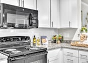 Thumbnail 11 of 39 - A black stove top oven with a black microwave above it.
