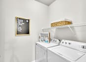 Thumbnail 16 of 39 - A laundry room with a washer and dryer and a framed sign on the wall.