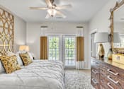 Thumbnail 19 of 39 - A bedroom with a large bed, a dresser, and a ceiling fan.