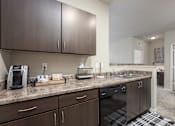 Thumbnail 3 of 40 - A kitchen with dark brown cabinets and granite countertops.