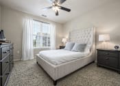 Thumbnail 8 of 40 - A bedroom with a large bed, a dresser, and a ceiling fan.